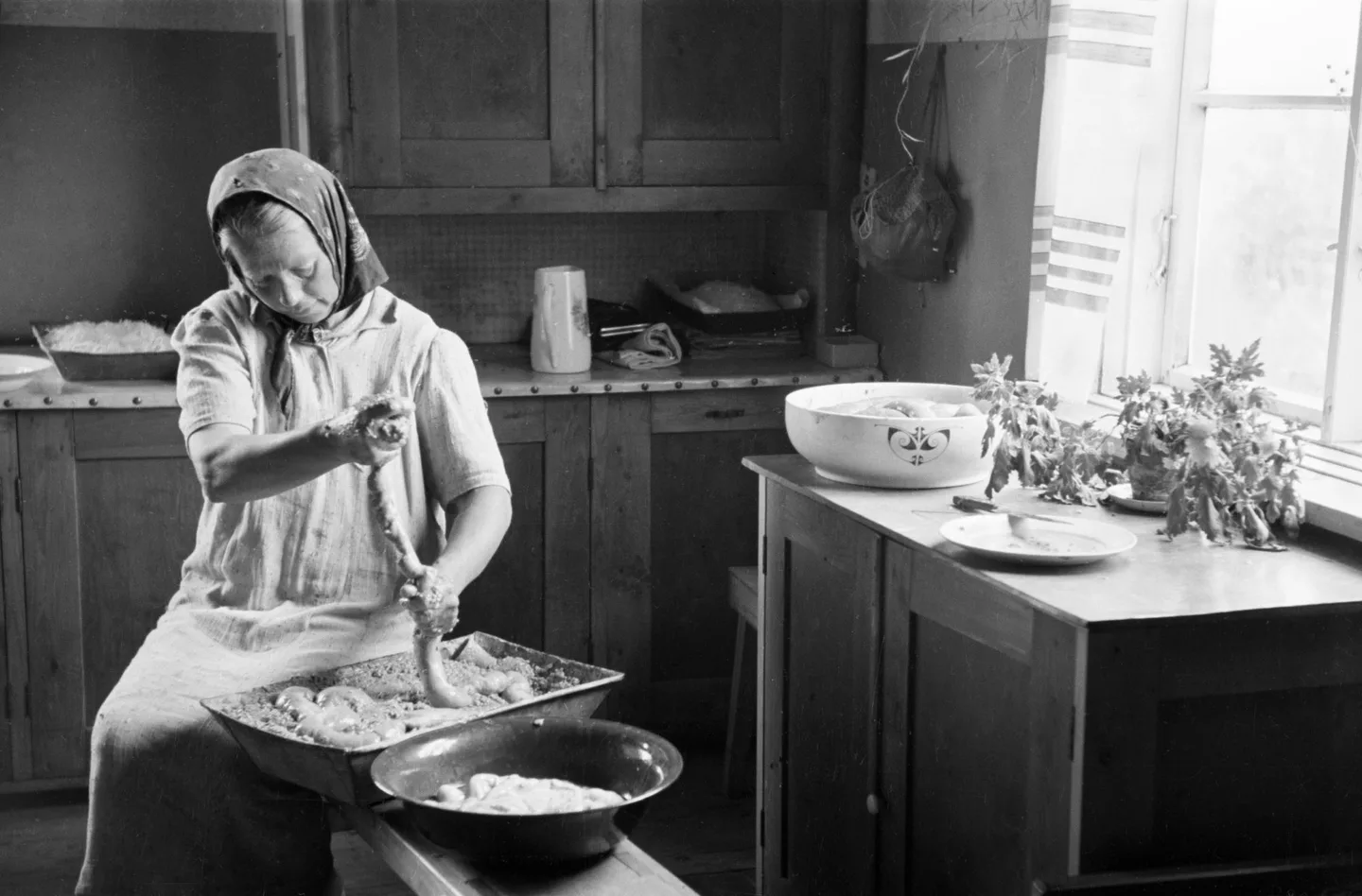 Nainen valmistaa makkaraa. Kuva: Väinö Aleksi Kannisto (1940-1949), Helsingin kaupunginmuseo, Finna.fi