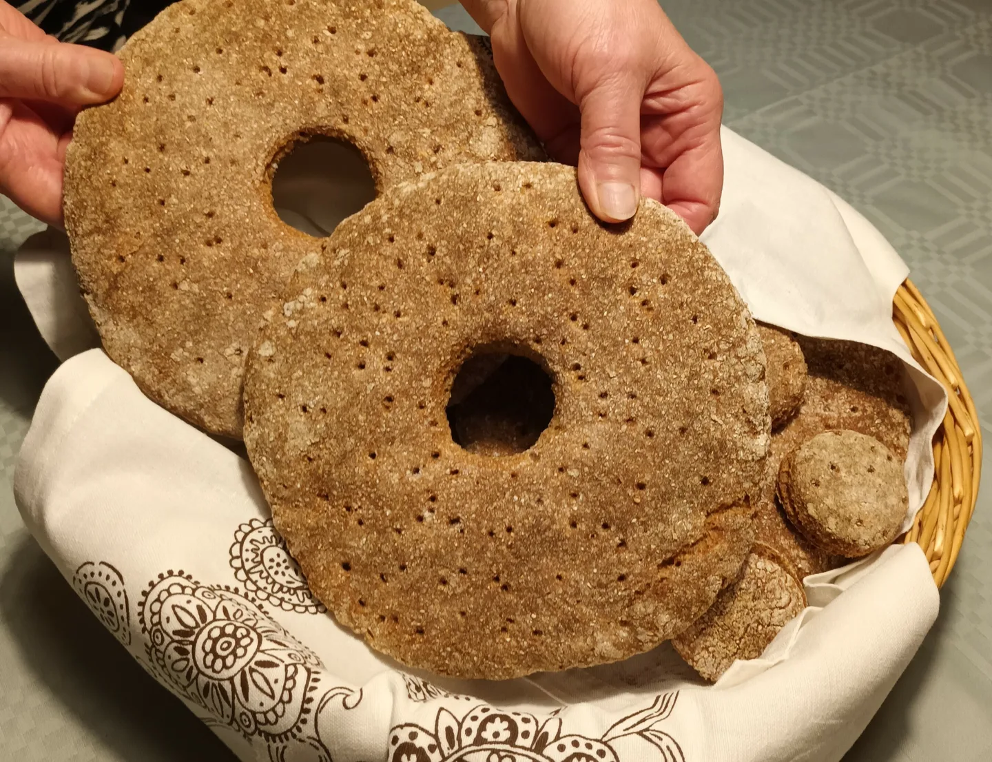 Kaksi rukiista reikäleipää ja leivän reikiä leivinliinan sisällä leipäkorissa