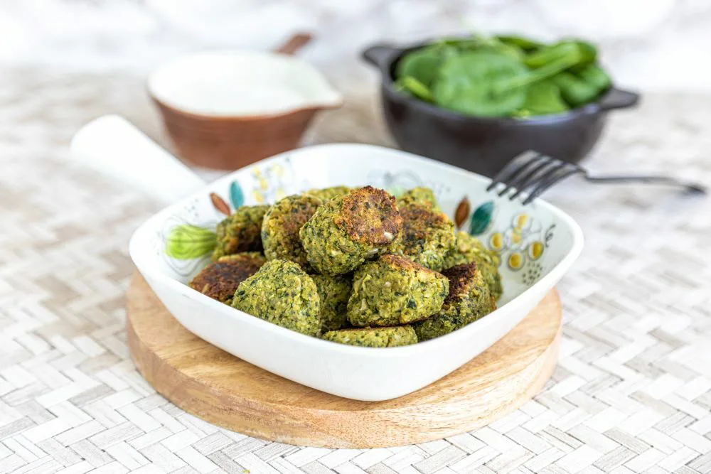 vihertäviä kasvispyöryköitä kulhossa, taustalla valkoista kastiektta ja pinaattia kulhoissa