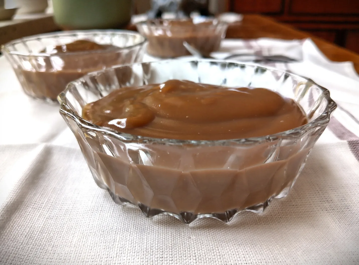 Kolme lasikulhoa joissa maitokahvikiisseliä