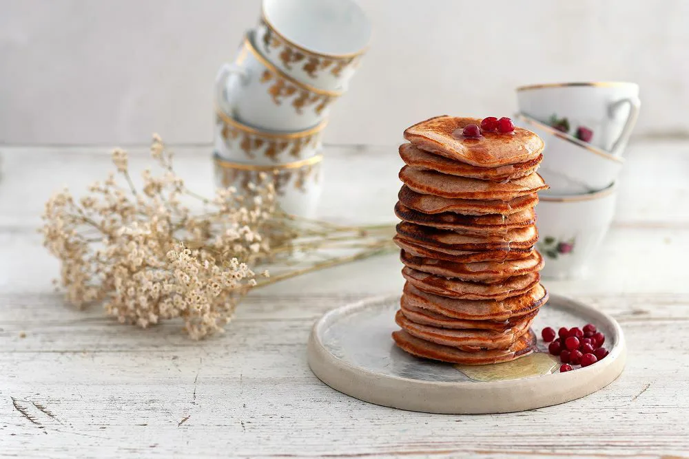 pinossa lettuja, päällä ja vierellä puolukoita, kahvikuppeja pinossa takana