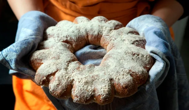 Kranssinmuotoinen yrttileipä ja leipurin kädet