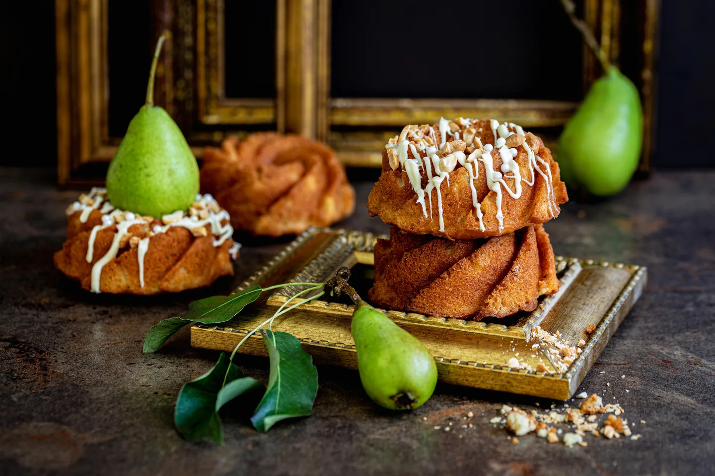 Pieniä sulatetulla valkosuklaalla koristeltuja kakkkusia, päärynöitä ja pähkinärouhetta