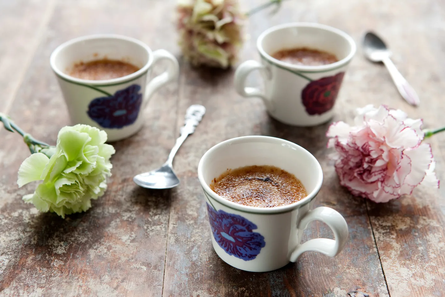 paahtovanukkaita kahvikupeissa, kukkia ja lusikoita