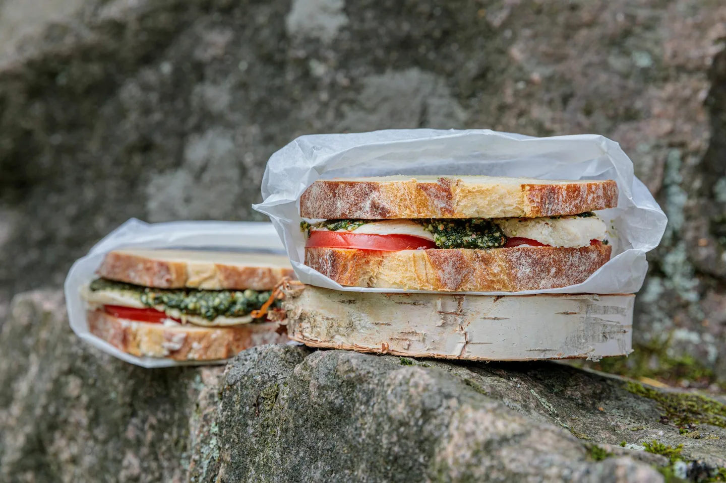 Kuvassa kerrosvoileipä, jonka välissä pestokastiketta, tomaattia ja kanaa. Voileipä pakattu eväspussiin.