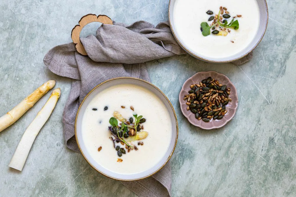 Parsakeittoa lautasilla. Siemenripotetta keiton päällä. Lautasten alle asetettuna pyyhe.